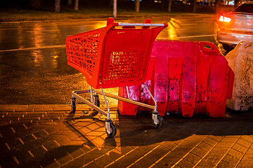 plastic red grocery cart left on a rainy evening near the road