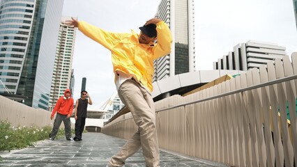 Happy hipster perform break dance while friend moving to music together. Handsome cool street...