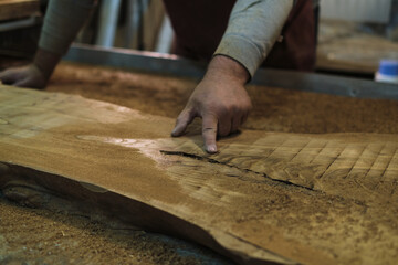 The woodworker examines the grain patterns of a beautiful burl slab. Each line and knot narrates the history of the tree.