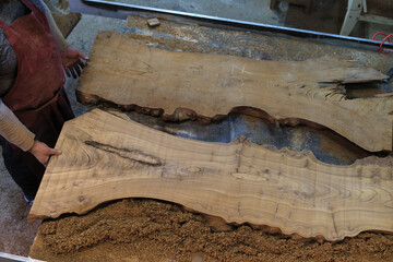 A craftsman admires the natural beauty of a large wood slab. The rich textures tell a story of the wood's life journey.