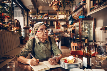 Senior waitress doing expenses at a restaurant table