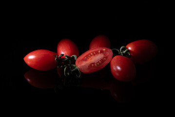 Group of red fresh bright tomato babies on a black background. Healthy vegetarian eating.