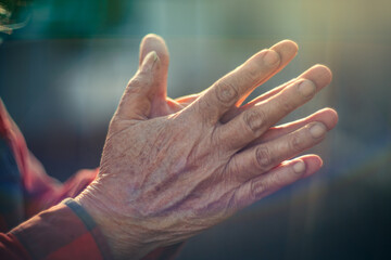 Old person hands put together in prayer gesture. Closeup, shallow DOF.