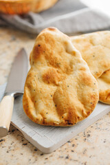 Freshly Baked Naan Bread on citting board on kitchen table.