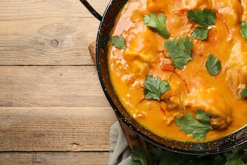 Tasty chicken curry with parsley on wooden table, top view. Space for text