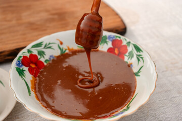 Homemade salted caramel sauce in Bowl with Spoon on table. Boiling Sugar for cooking caramel.