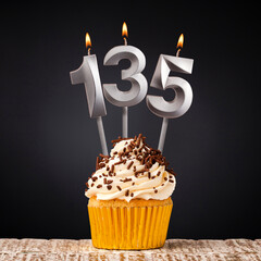 birthday cupcake with number 135 candle - Celebration on dark background