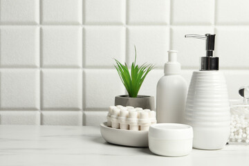 Fototapeta na wymiar Different bath accessories and personal care products on white table near tiled wall, space for text