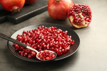 Ripe juicy pomegranate grains on grey table