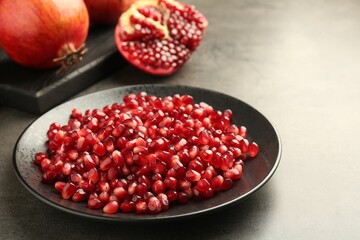 Ripe juicy pomegranate grains on grey table
