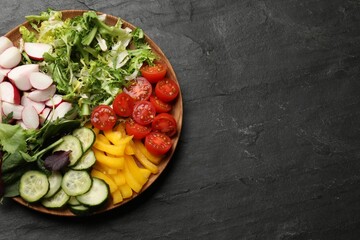 Vegetarian diet. Plate with tasty vegetables on black table, top view. Space for text