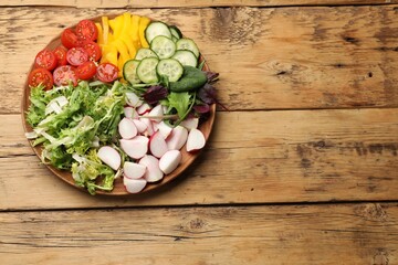 Vegetarian diet. Plate with tasty vegetables on wooden table, top view. Space for text