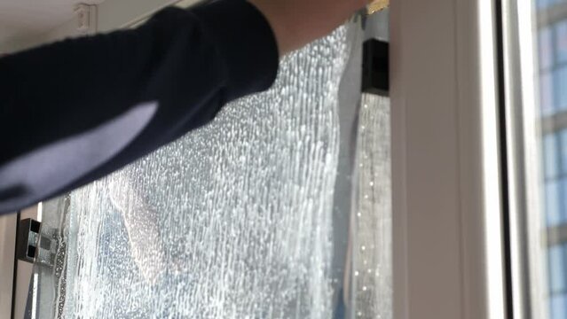 Worker installing tint film on window at home. Man tinting windows