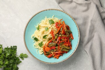 Vegetarian meal. Tasty pasta with vegetables on light grey marble table, top view