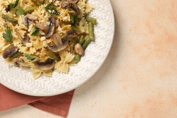 Vegetarian pasta with mushrooms, parsley, string beans and cheese on orange textured table, top...