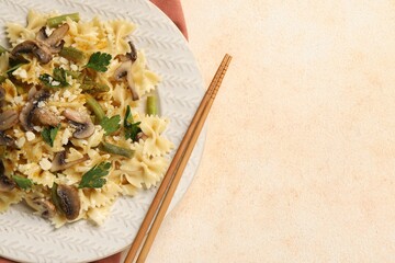 Vegetarian pasta with mushrooms, parsley, string beans and cheese on orange textured table, top...