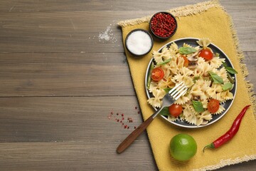 Vegetarian pasta with mushrooms, basil, string beans and tomatoes on wooden table, top view