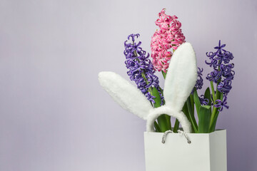 shopping bag, flowers and Easter bunny ears. lilac, pink hyacinth flowers, light background.