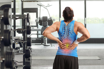Male athlete stretching his back with red inflamed spot at a gym