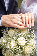 wedding bouquet in the hands of the bride and hands with rings of the newlyweds