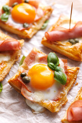 Puff pastry egg and ham mini tarts, focus on the tart with egg, close up view. Delicious breakfast or Easter snack - 758334799