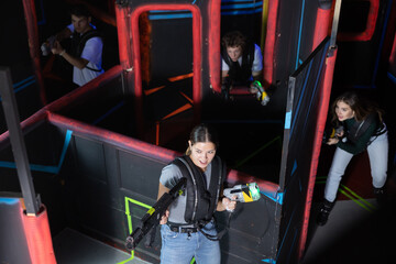 Four people having fun playing lasertag ducking behind cover in maze of lasertag arena
