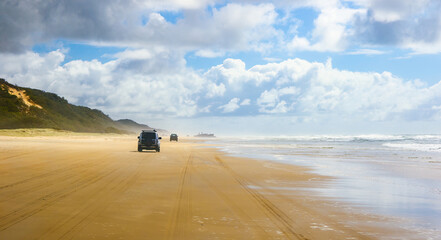 4WD trucks driving offroad on the Fraser island beach track near the SS Maheno shipwreck, half...