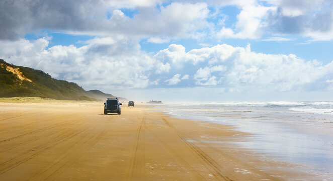4WD trucks driving offroad on the Fraser island beach track near the SS Maheno shipwreck, half buried in the sand of the 75 mile beach on the east coast of the island in Queensland, Australia