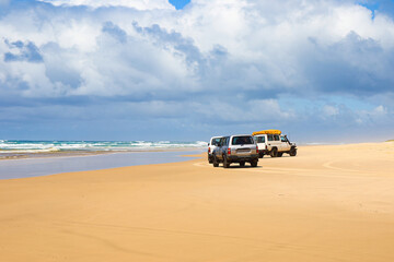 Fototapeta na wymiar 4WD trucks offroad on the Fraser island beach track near Indian Head on the 75 mile beach on the east coast of the island in Queensland, Australia