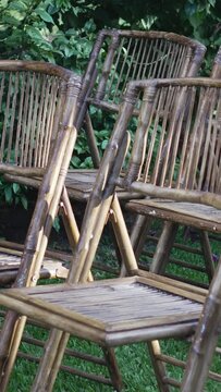 A row of bamboo chairs are placed on a grass area arranged in a row for the wedding ceremony.