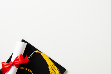 College graduation concept. Flat lay mortarboard cap with diploma on white background.