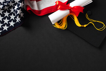 Graduation hat, diploma, American flag on black background. Flat lay, top view.