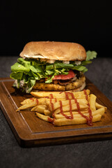 Delicious vegan burger containing chives, mushrooms, tomato, arugula, basil pesto and vegan mayonnaise with French fries