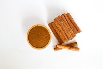 raw cinnamon material and powder in a wooden bowl