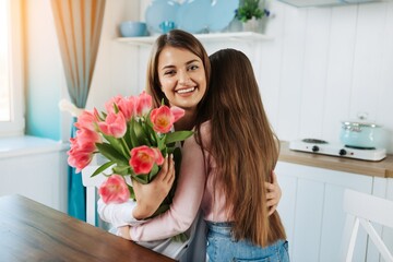 Happy mother's day! child daughter congratulates mother and gives a bouquet of flowers to tulips.