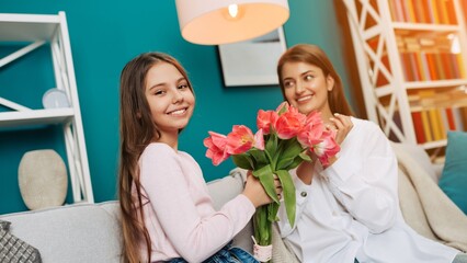 Happy Mother`s day! Beautiful girl giving a bouquet of pink tulips to her mother. Celebration at...