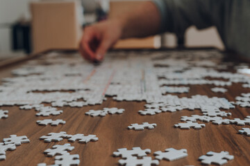 Puzzle pieces on a table, male hand placing a piece on the background.