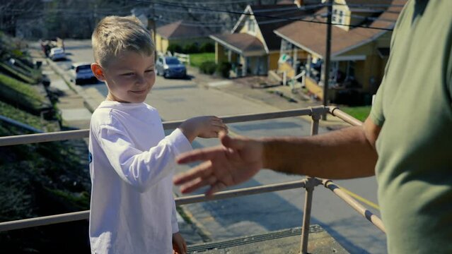 A grandfather and grandson perform a celebratory fist bump outside. Slow motion.  	