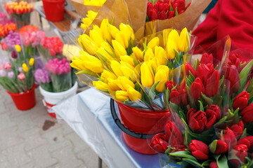 A table with a variety of flowers, including yellow and red tulips