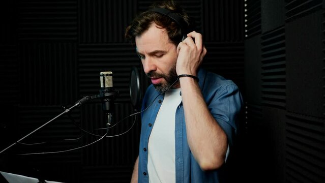 Caucasian voiceover artist with headphones recording some voice lines in a professional studio setting