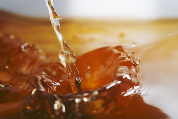 Macro shot of golden liquid splash made up of melting gummy bear in hot water