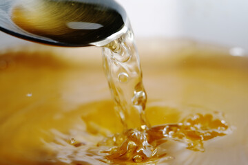 Macro shot of golden liquid splash made up of melting gummy bear in hot water