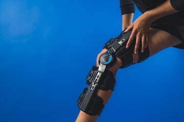 woman with a bandage compression knee brace on a blue background, healthcare and medical concepts. High quality photo