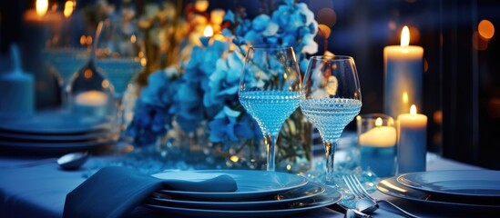 The table is adorned with plates, glasses, candles, and flowers, creating a serene atmosphere with liquid candles, azure glasses, and aqua flowers for an electric blue themed event