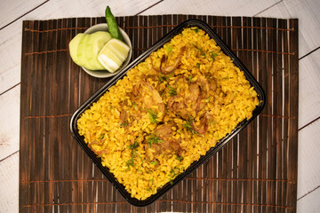 Chicken khichuri biryani rice pulao with cucumber and lemon slice served in dish isolated on wooden...