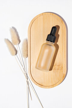 Frosted glass cosmetic bottle with pipette, product packaging with dry lagurus leaf, anti aging serum with peptides, cosmetics mockup, spa concept.