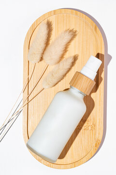 Anti-aging collagen facial cream in frosted glass bottle on wooden tray on white background with copy space. Natural Organic Cosmetic Beauty Concept.