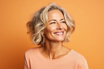 Portrait of beautiful middle aged woman with blond hair on orange background