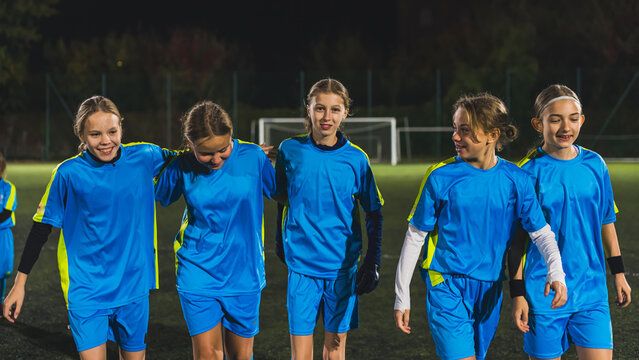 medium shot of a group of cute little girls wearing blue uniforms at the football practice at night. High quality photo