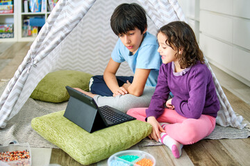 Siblings engaging in creative play with hama beads and tablet